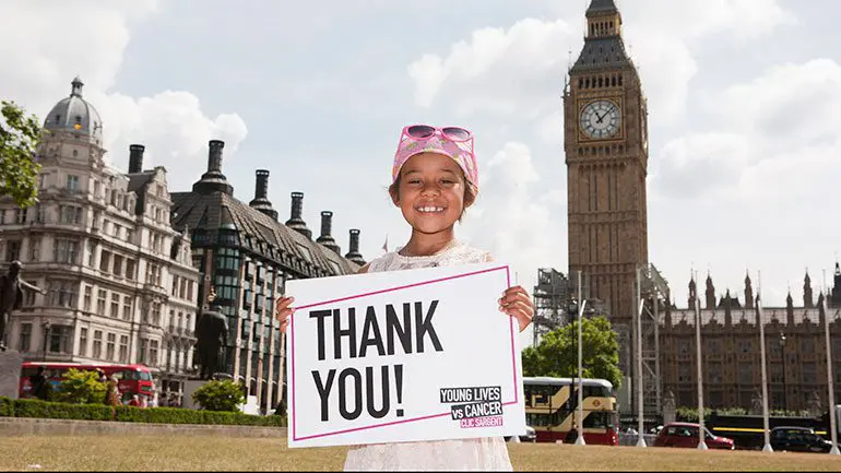 Young cancer patient Khianna holding a Thank You sign outside of parliament