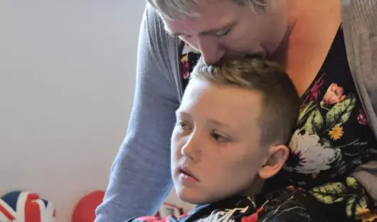 A mum kisses the top of her child's head