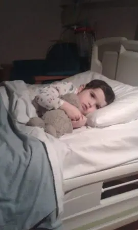 Heidi in hospital during her cancer treatment, holding a cuddly toy