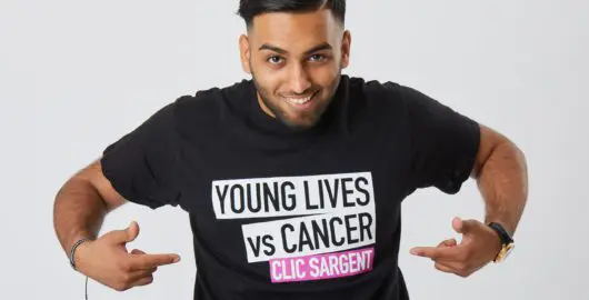 Boy pointing at Young Lives vs Cancer logo on shirt