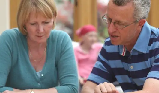 Two parents read a document while their child with cancer sits in the background