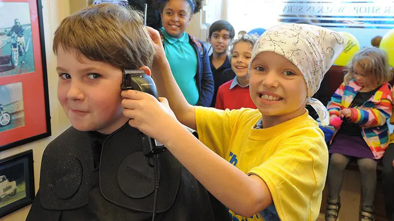 James, 10, having his head shaved by his girlfriend Ivy, who was diagnosed with cancer