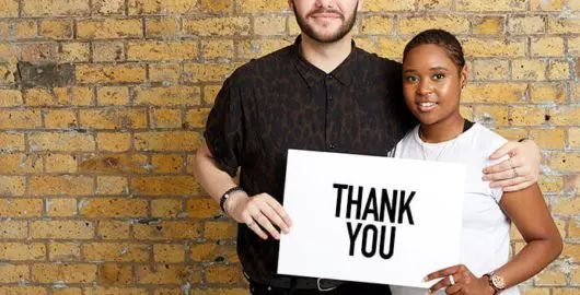 Two people holding a sign saying thank you