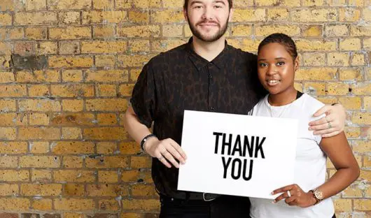 Two people holding a sign saying thank you
