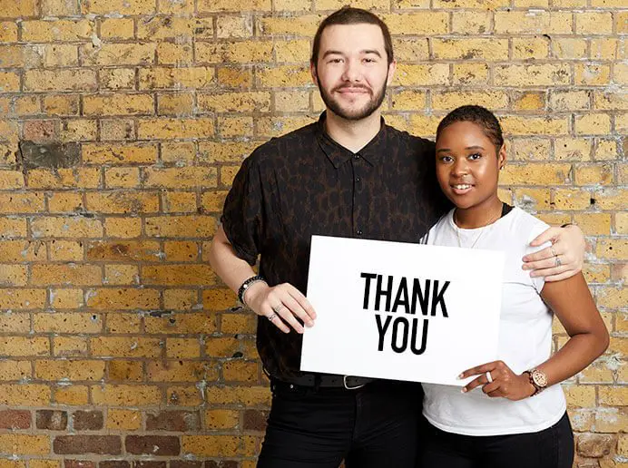 Two people holding a sign saying thank you