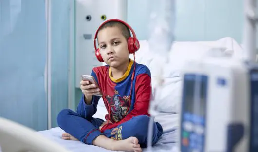Boy Holds iPhone on Hospital Bed
