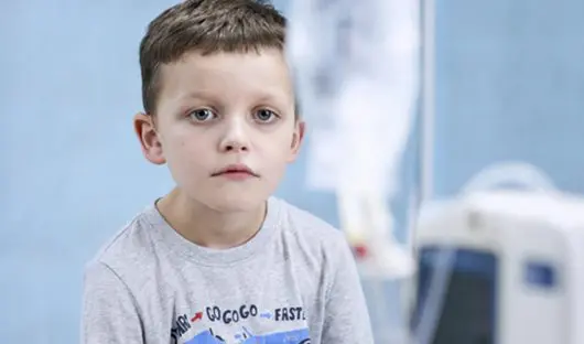 Small child next to a piece of hospital machinery