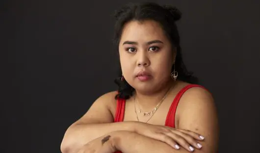 A young person baring a thoughtful expression with her arms crossed