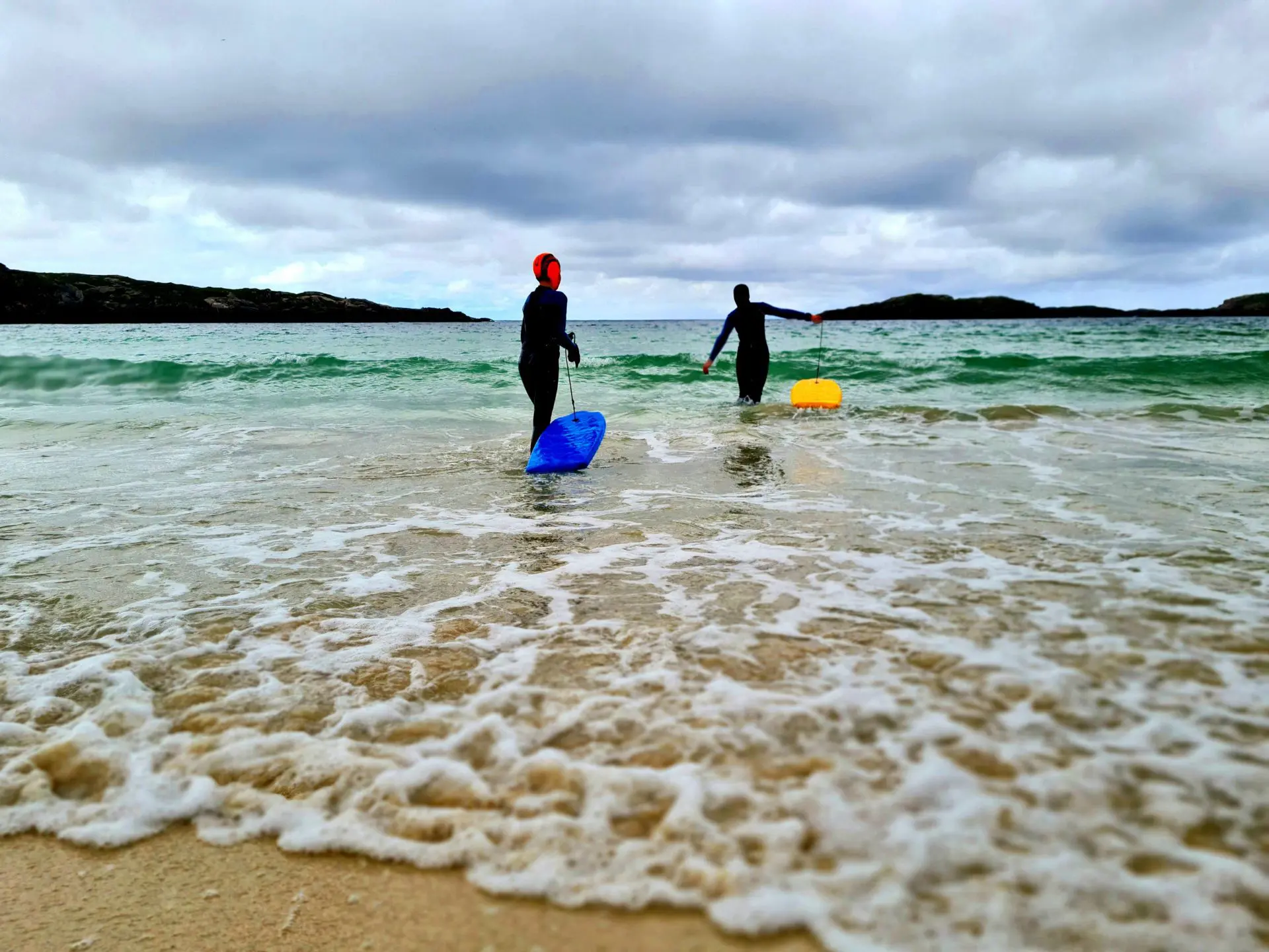 Children playing in the sea with body boards