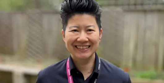 Lyn Soh wearing a lanyard with an NHS rainbow badge on it