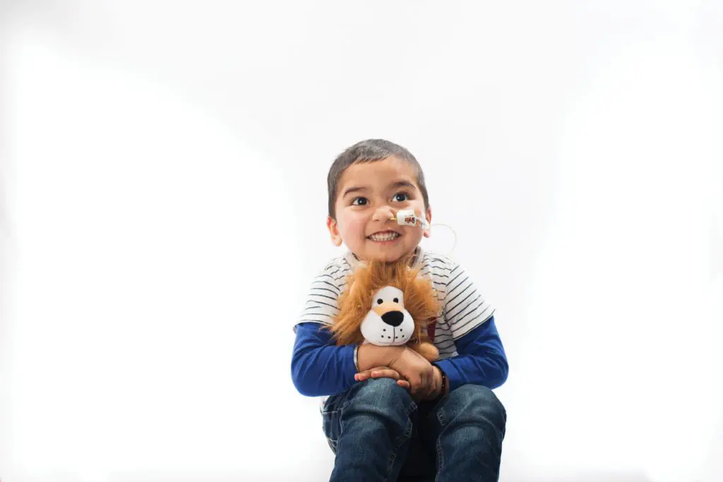 Young cancer patient hugging his cuddly lion toy
