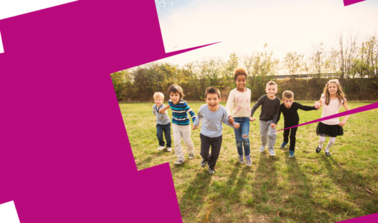 Web banner. image shows a group of 7 children all holding hands in a line, running towards the camera, smiling and looking excited