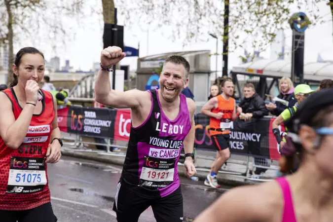 Young Lives vs Cancer London Marathon runner holds fist in triumph while running