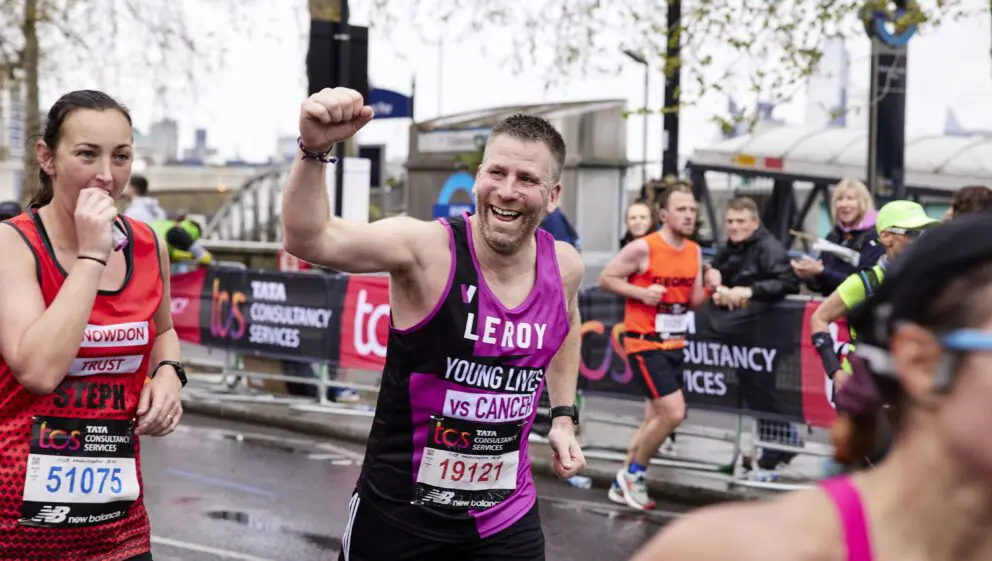 Young Lives vs Cancer London Marathon runner holds fist in triumph while running