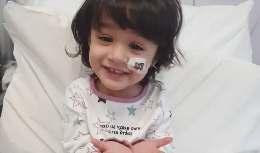 Young cancer patient Aasiyah smiling in a hospital bed