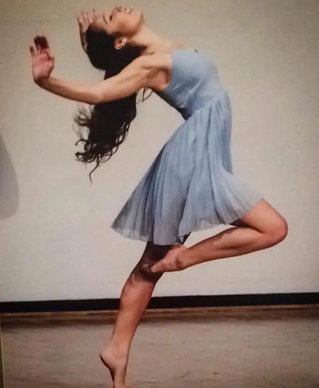 Amy is wearing a blue dress, the photo has been taken while she is in the middle of a dance