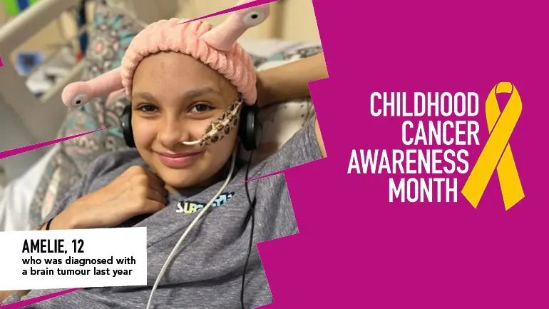 Amelie smiling with headphones and pink alien beanie. The text on the bottom right of the image says "Childhood Cancer Awareness Month" with a gold ribbon and a purple underlay.