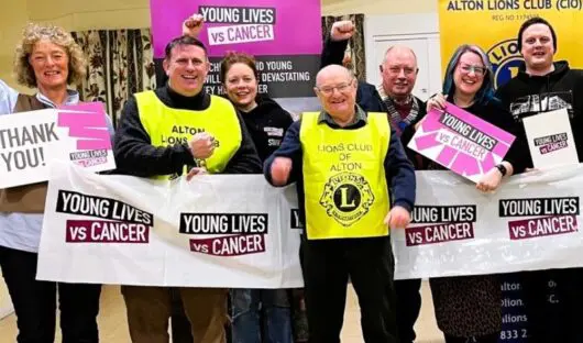 Group of people holding banners and signs, smiling