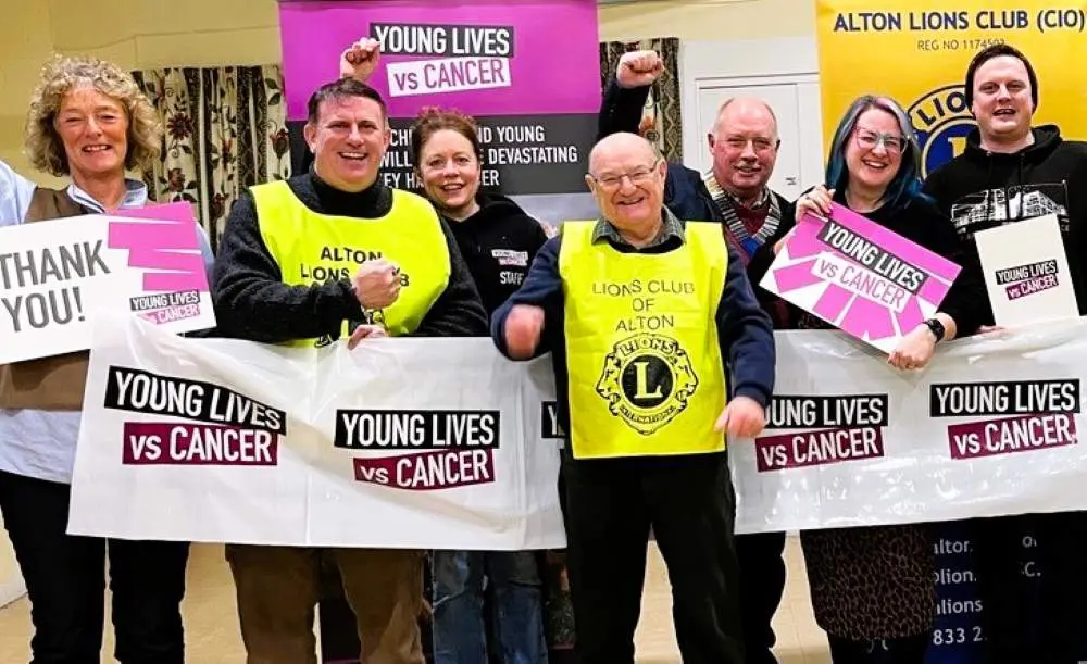 Group of people holding banners and signs, smiling