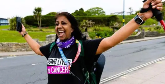 Woman in Young Lives vs Cancer T-shirt, walking looking very happy!