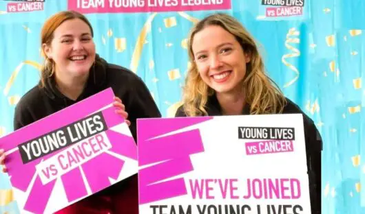 Two smiling women holding signs saying 'we've joined Team Young Lives'