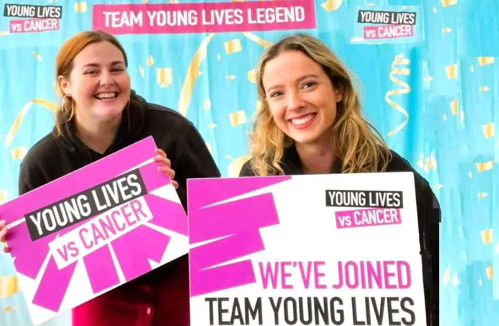 Two smiling women holding signs saying 'we've joined Team Young Lives'