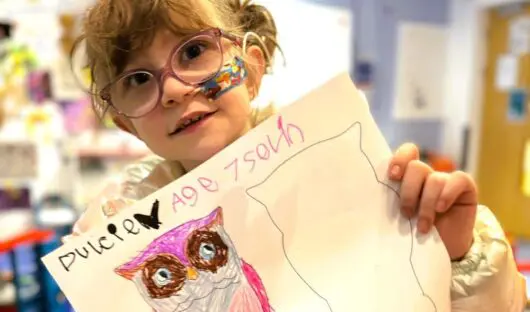 Young girl, aged 7 holding up her artwork of an owl
