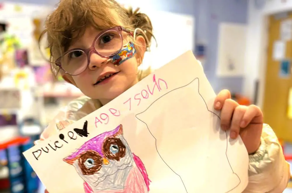 Young girl, aged 7 holding up her artwork of an owl