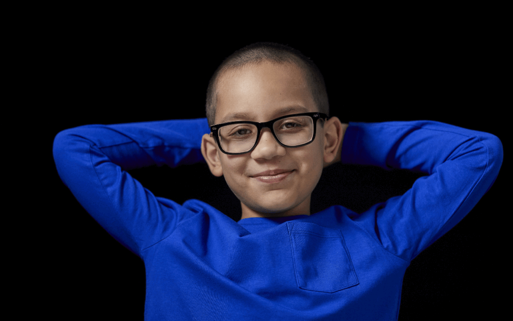 Young person in a blue jumper and glasses smiling at the camera