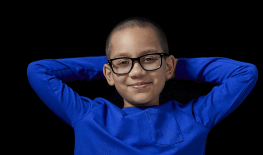 Young person in a blue jumper and glasses smiling at the camera