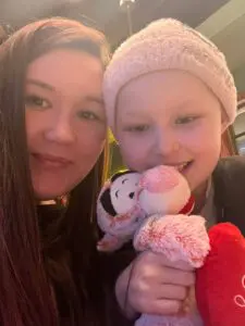 Ava and Katie smiling at the camera. Ava is holding a soft toy