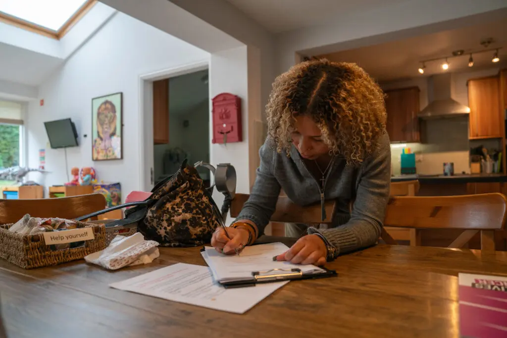 A young person sat at a kitchen table completing paperwork. 