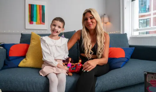 Child and their mum sat on a sofa at on of Young Lives vs Cancer's homes from home.