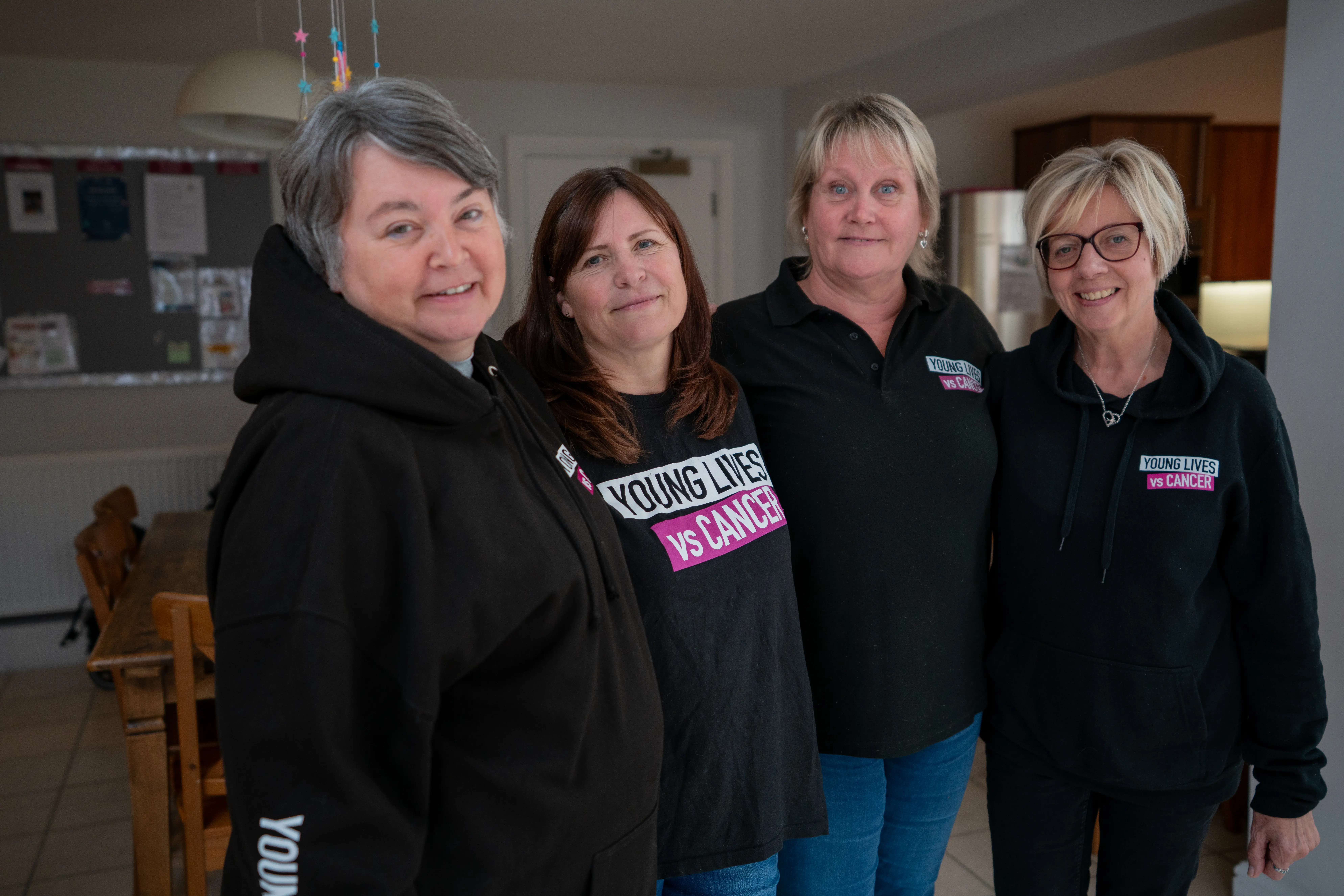 Young Lives vs Cancer accommodation team members in branded hoodies smiling at the camera.