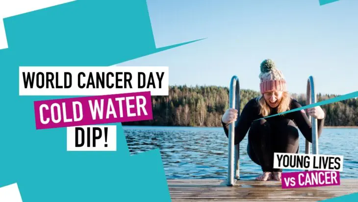 A woman wearing a wetsuit and beanie, preparing to take a dip in a cold river.