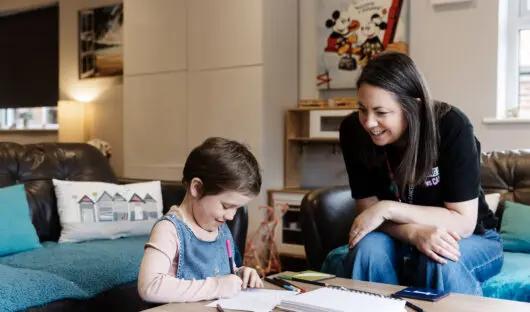 Young Lives vs Cancer specialist social worker sat with a young person who is drawing.