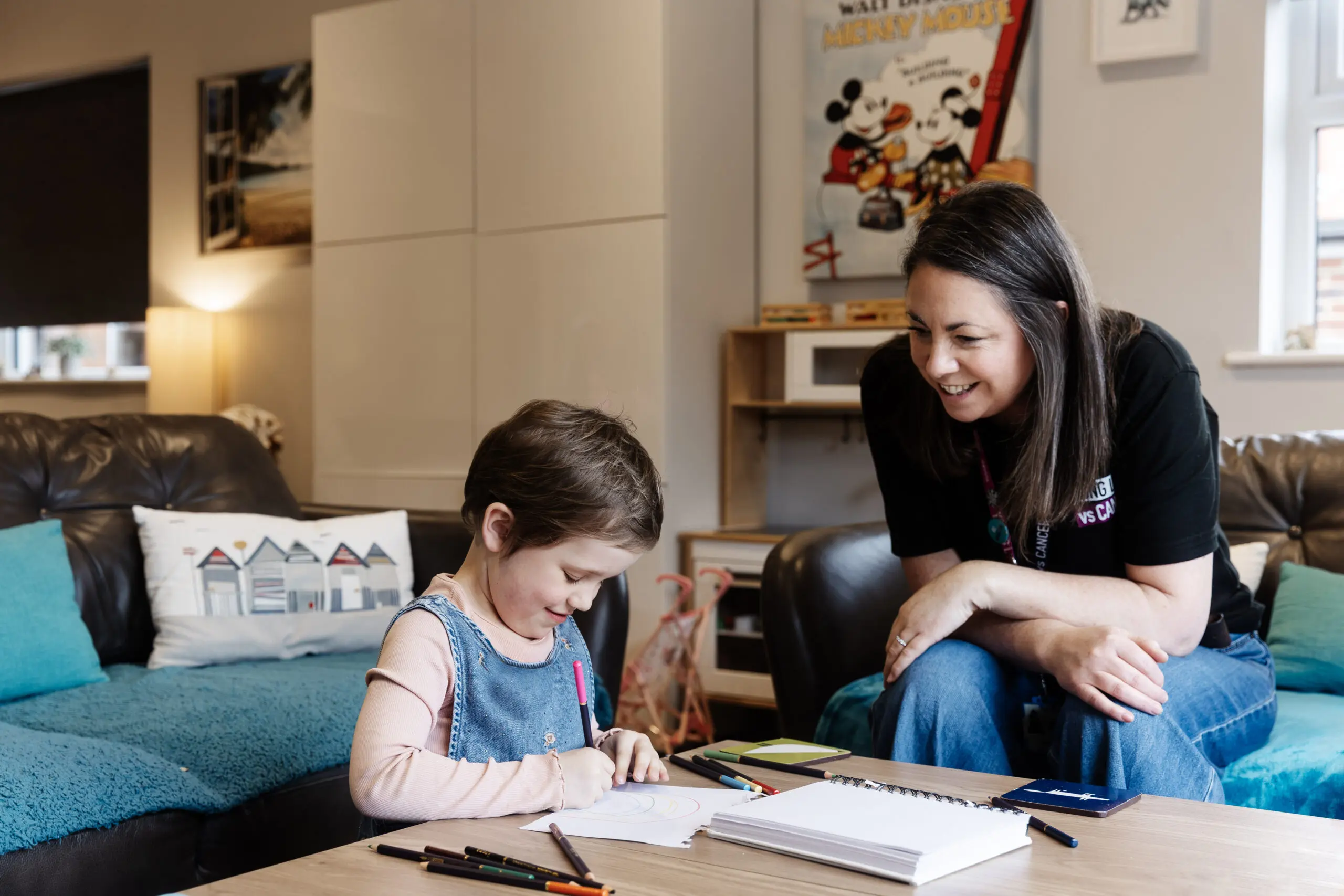 Young Lives vs Cancer specialist social worker sat with a young person who is drawing.