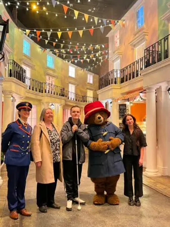 A photographer of 17 year old Jack with his nan Elaine, actor Madeleine Harris, and Paddington Bear at the Paddington Experience during his One Big Thank You surprise