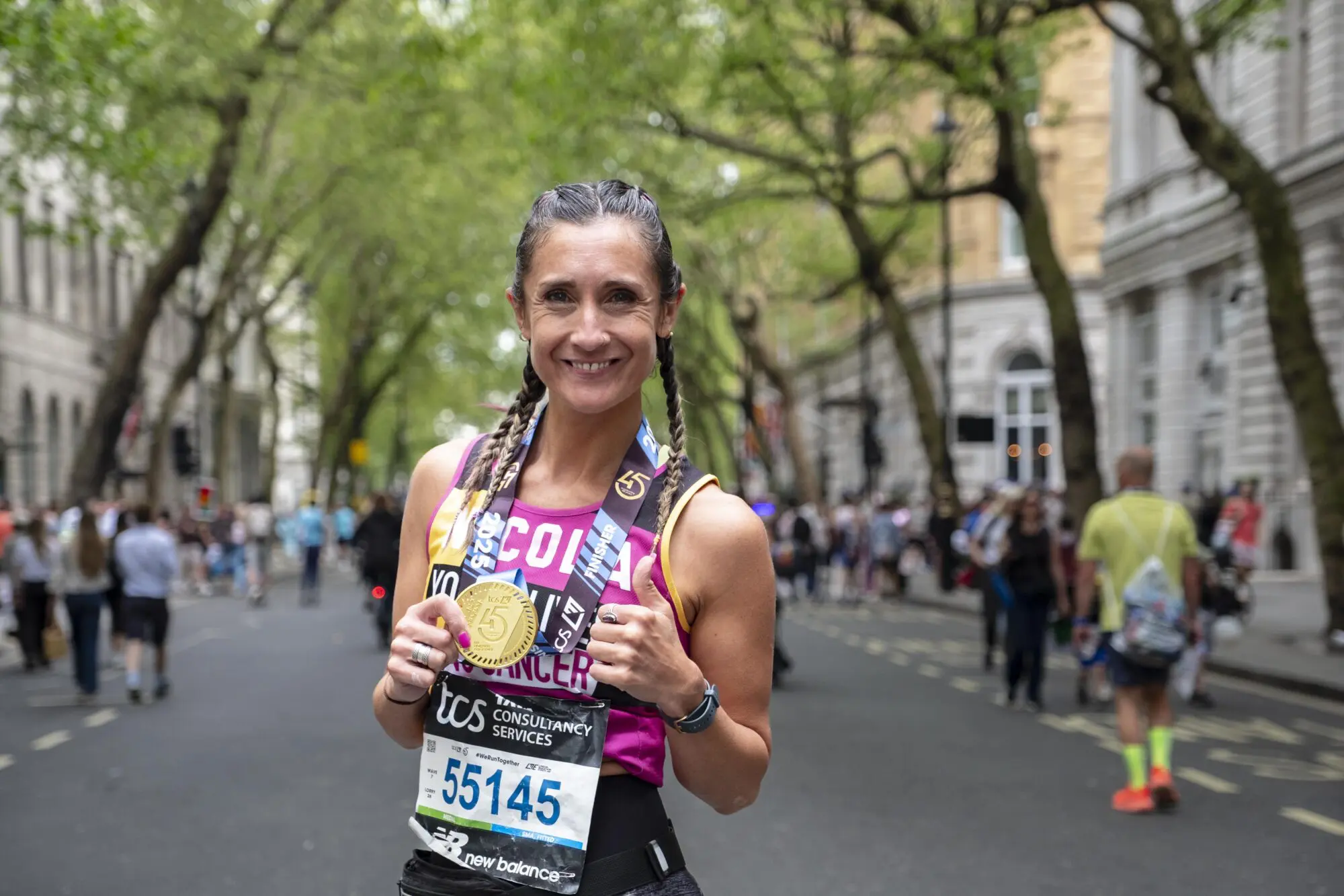 A Young Lives vs Cancer runner after the London Marathon smiling and holding their medal