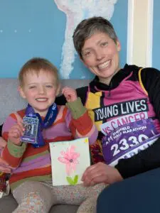 Sarah and her daughter Maya. Sarah is wearing a Young Lives vs Cancer running vest and Maya has a marathon medal around her neck.