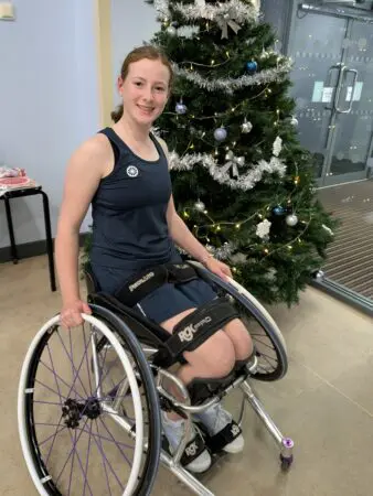 Lucy sat in her wheelchair in front of a christmas tree