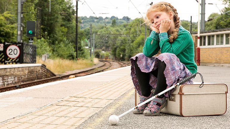 Young cancer patient Eliza waiting at a train station