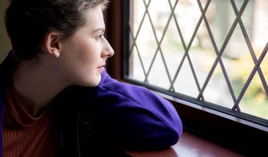 A teenager with cancer looks out of a window