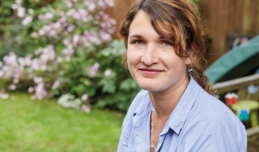 A mum of a child with cancer sits in her garden smiling
