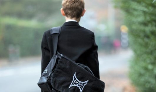 A child who has had cancer makes his way to school