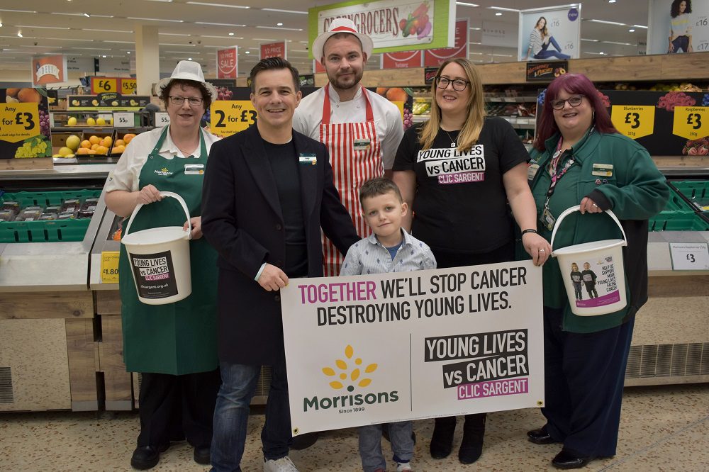 Morrisons and CLIC Sargent hold banner in a supermarket to mark the 4th year of the partnership