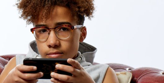 A boy sitting on the sofa, using his mobile phone