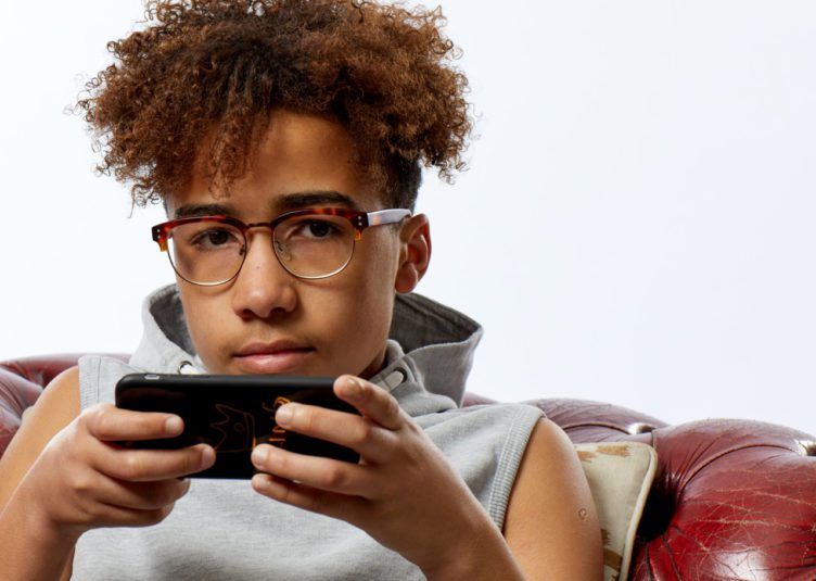 A boy sitting on the sofa, using his mobile phone