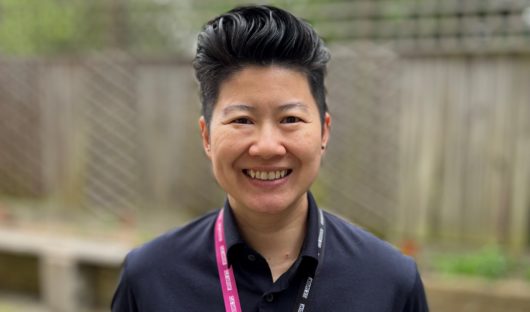 Lyn Soh wearing a lanyard with an NHS rainbow badge on it