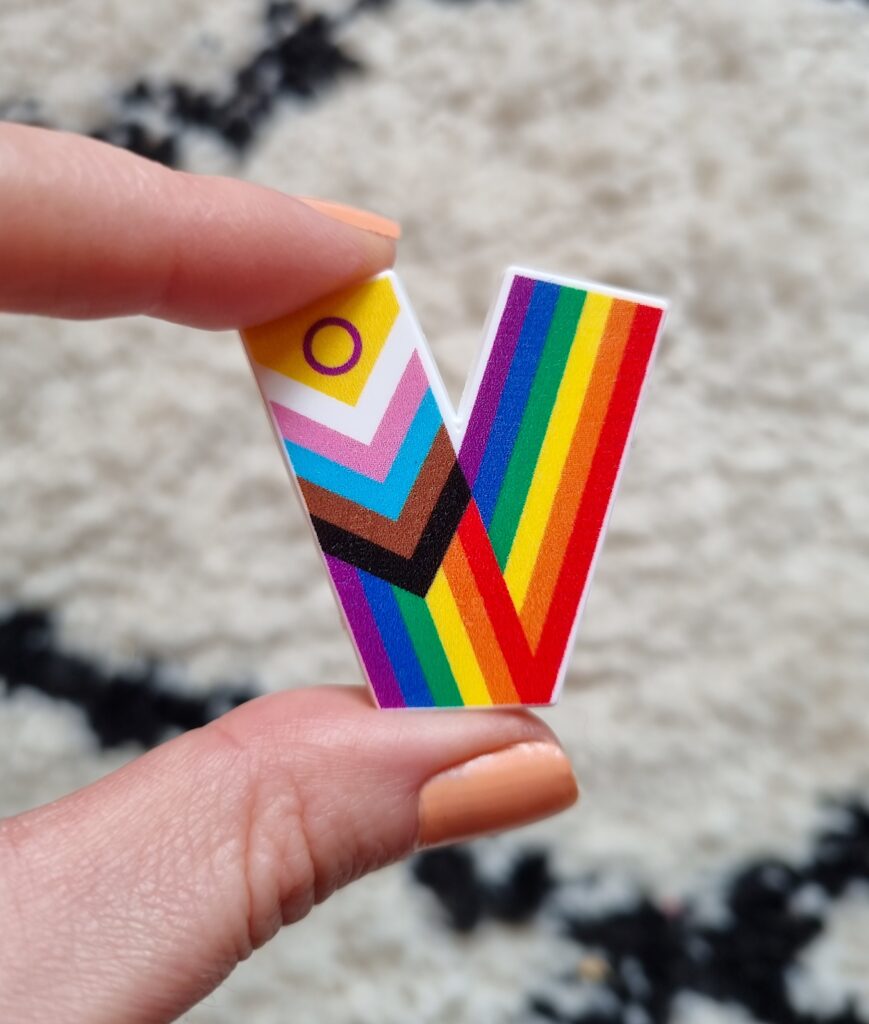 The Young Lives vs Cancer Pride badge in a V shape with the colours of the Pride flag